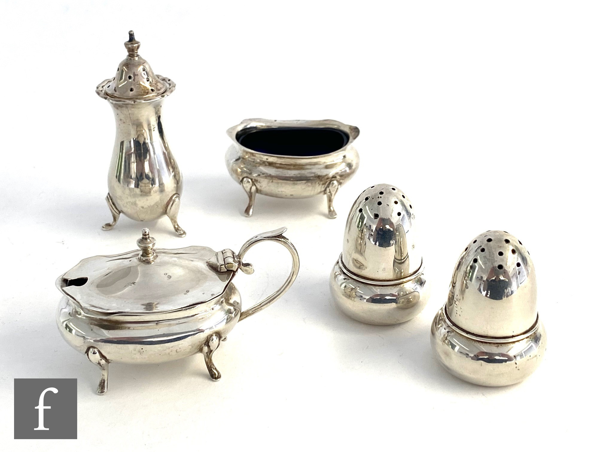 A hallmarked three piece boat shaped cruet set with a pair of silver peppers modelled as a acorns,