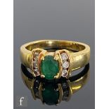 An 18ct hallmarked emerald and diamond three stone ring, central oval emerald flanked by three