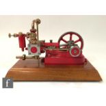 A Stuart single cylinder horizontal engine, painted red with six spoked flywheel, raised to a