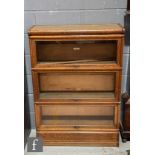 An early 20th Century Globe Wernicke three-tier oak bookcase on a plinth base, labelled, S/D.