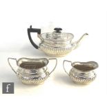 A hallmarked silver boat shaped three piece tea set with part fluted decoration and ebonised