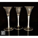 A set of three 18th Century drinking glasses circa 1765, the drawn trumpet bowl above a double