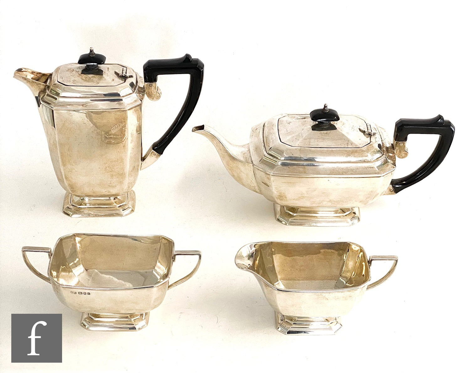 A hallmarked silver Art Deco four piece pedestal tea set of plain faceted boat shaped form,