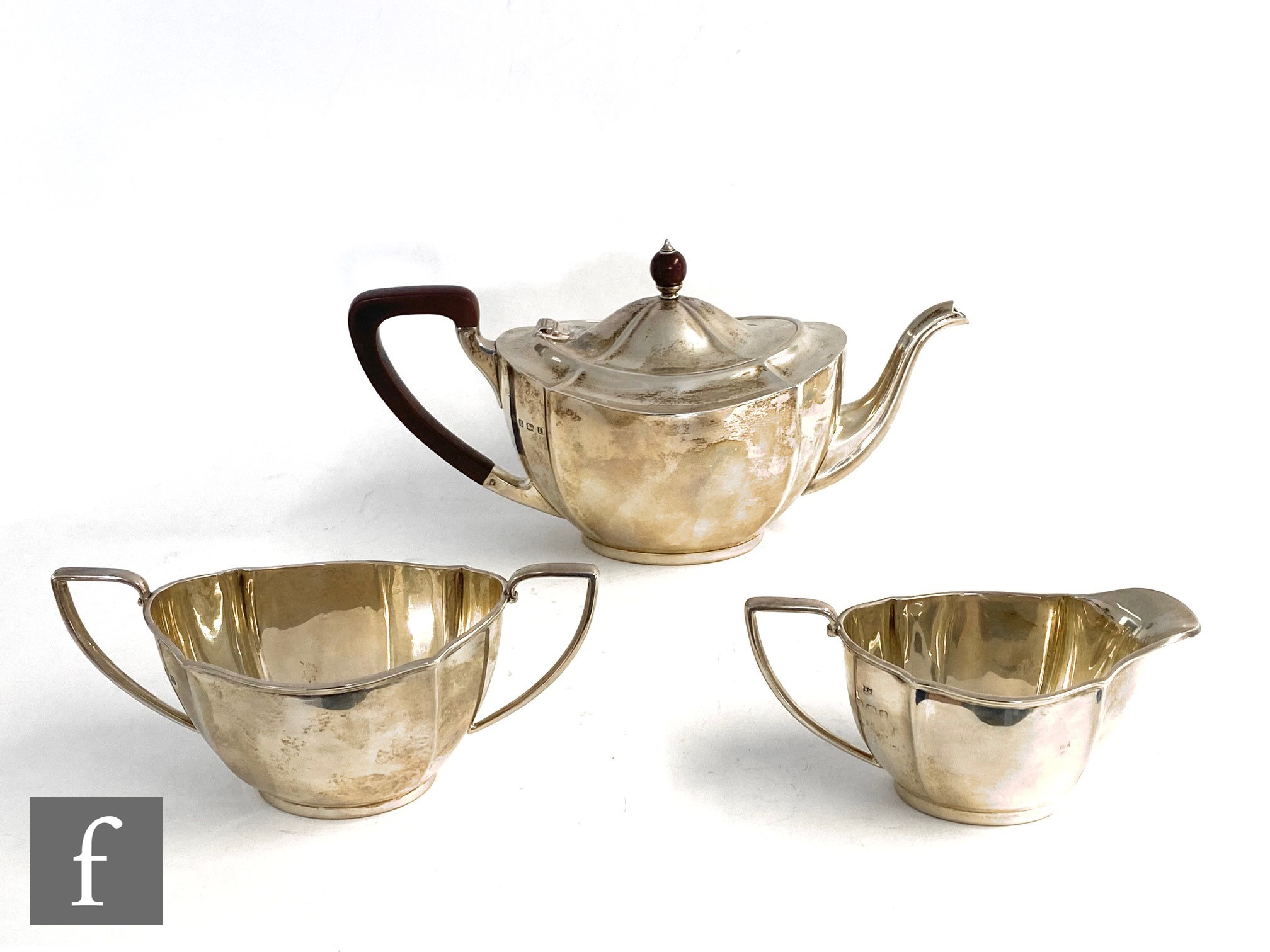 A hallmarked silver boat shaped and cushioned faceted three piece tea set terminating in angular