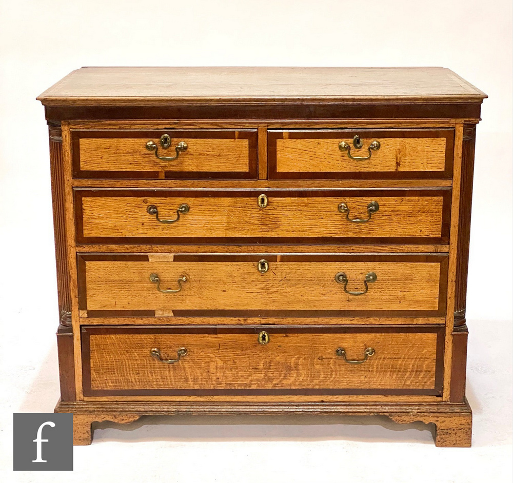A George III oak and mahogany crossbanded chest of two short and three long drawers, brass drop