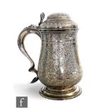 A George III hallmarked silver baluster tankard terminating in scroll handle with heart motif,