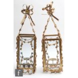 A pair of gilt metal and glass hanging lanterns, the four glass square section shades, applied