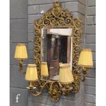 A late 19th to early 20th Century pierced brass girandole wall mirror, the bevelled rectangular