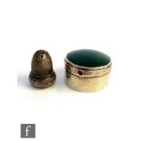 A hallmarked silver circular pill box with inset nephrite to hinged cover and red stone to thumb