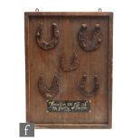 A wooden display board mounted with five iron horse shoes, bears painted plaque 'Found at the site