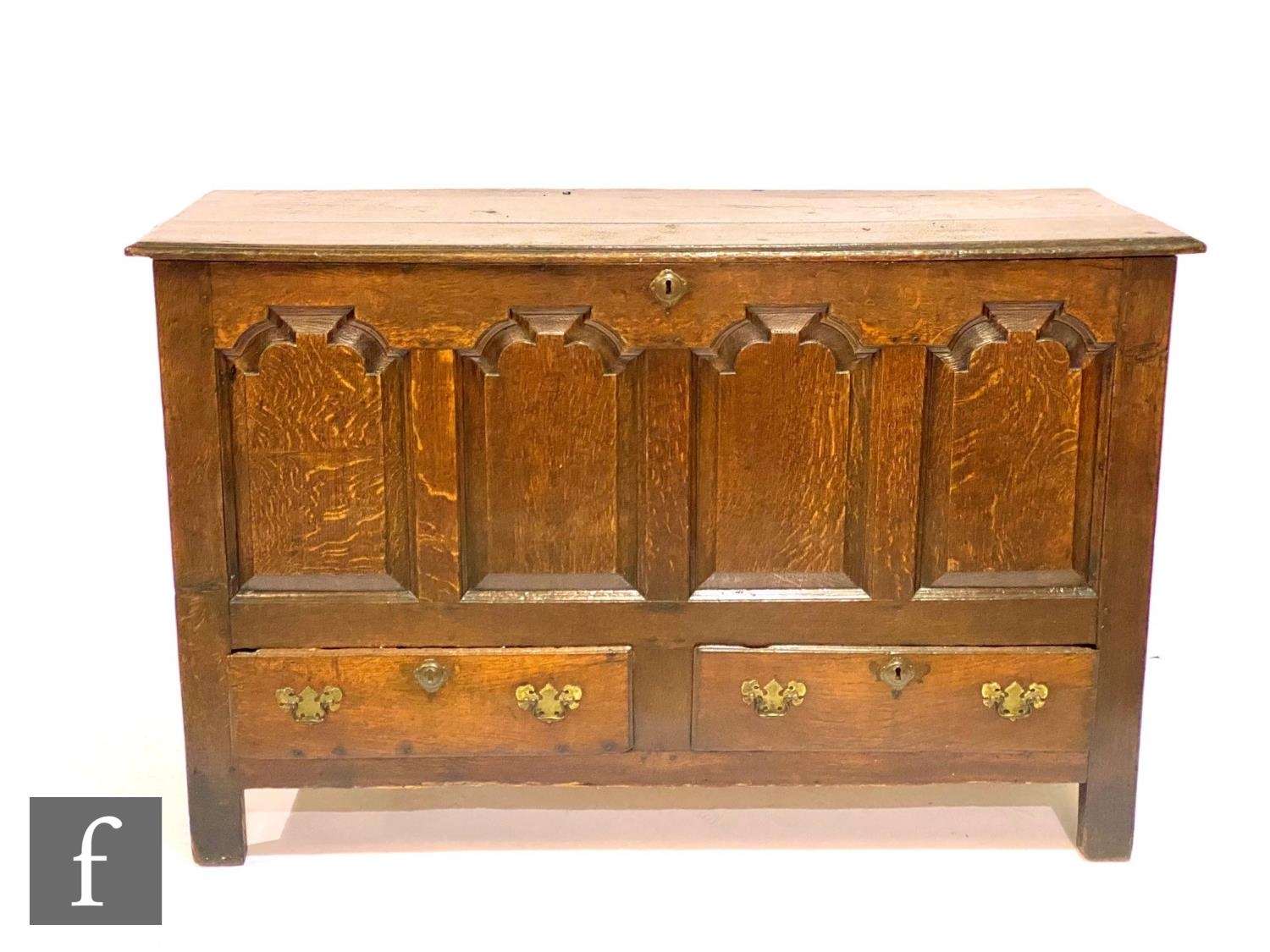 An 18th Century oak mule chest, the twin plank top over a quadruple panel front above two drawers on