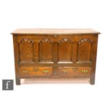 An 18th Century oak mule chest, the twin plank top over a quadruple panel front above two drawers on