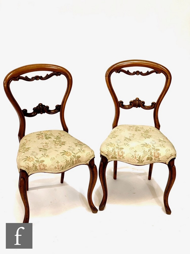 A set of four Victorian mahogany salon chairs, carved scroll splats, on cabriole legs, upholstered