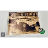 An Aston Martin Le Mans winners 1959-2009 enamel car badge and a large signed photo of Roy
