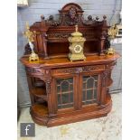 A late Victorian walnut break-fronted side display cabinet, with a mask and swagged garland pediment