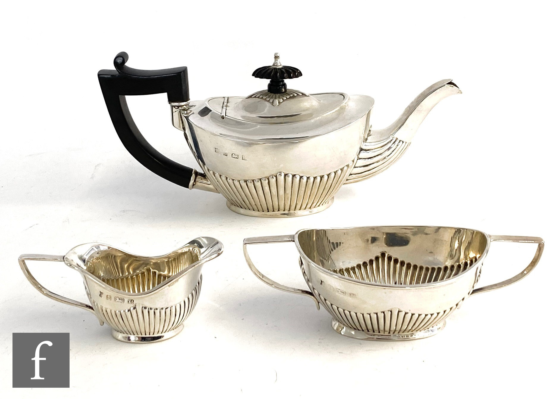 A hallmarked silver three piece bachelor's tea set of part fluted boat shaped form, total weight