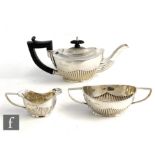 A hallmarked silver three piece bachelor's tea set of part fluted boat shaped form, total weight