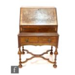 An early 20th Century cross-banded walnut bureau on stand on the William and Mary style, with a
