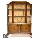 An Edwardian figured walnut display cabinet with projecting serpentine glass sides and front