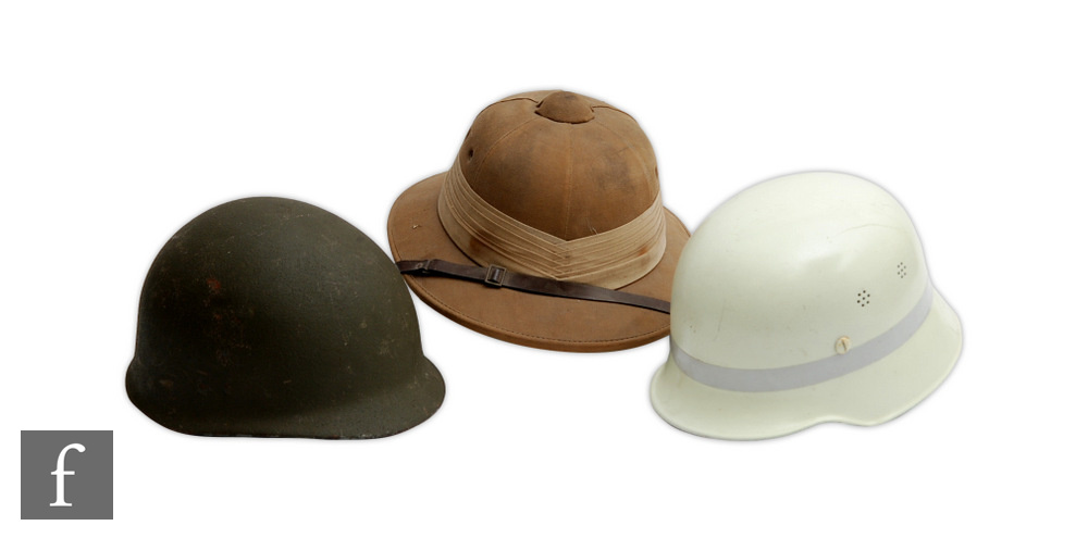 An American army helmet together with a pith helmet made by Wegener and a late 20th Century