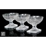 A set of three Georgian glass pedestal salts, each with an oval bowl cut with swags, and raised to a