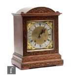 An Edwardian oak cased mantle clock with eight day striking movement enclosed by a glazed door below