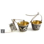 A pair of Russian silver gilt and nellio work bucket shaped tea strainers each with arched handle,