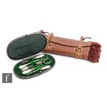 A late 19th Century oval leather case opening to seven steel sewing implements, with a brown leather