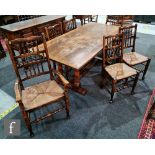 A 17th Century style oak refectory dining table on twin pillar supports united by a central