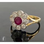 An 18ct hallmarked ruby and diamond daisy cluster ring, central collar set ruby to a brilliant cut