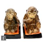 A pair of 1930s Myott book ends in the form of seated chimpanzees with enamelled decoration,