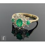 A 9ct hallmarked emerald and diamond cluster ring, three emeralds to a diamond set border and