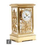 An Edwardian gilt metal mantle clock with eight day striking movement, the circular glass dial in