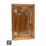 An early 19th Century stained pine hanging corner cupboard, the painted green interior enclosed by a
