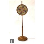 A 19th Century oak pole screen, the circular panel with Berlin beadwork decorative detail above a