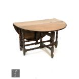 A 17th Century style oak drop flap oval dining table on bobbin turned legs united by rail