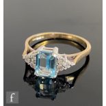 A 9ct hallmarked blue topaz and diamond ring, central emerald cut topaz flanked by three diamonds to