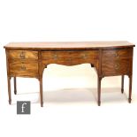 A George IV mahogany bow front sideboard fitted with four geometric inlaid drawers, oval brass