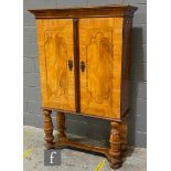 An early 18th Century and later walnut double door cabinet on later stand, with cornice pediment and