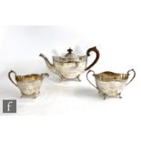 A hallmarked silver three piece boat shaped tea set of plain form, all raised on four scroll feet,