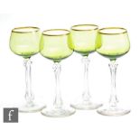 A set of four 20th Century wine glasses, the green ovoid bowl decorated with gilt rim, above a facet