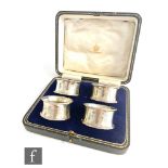 A cased set of four hallmarked silver waisted circular napkin rings of plain form each with raised