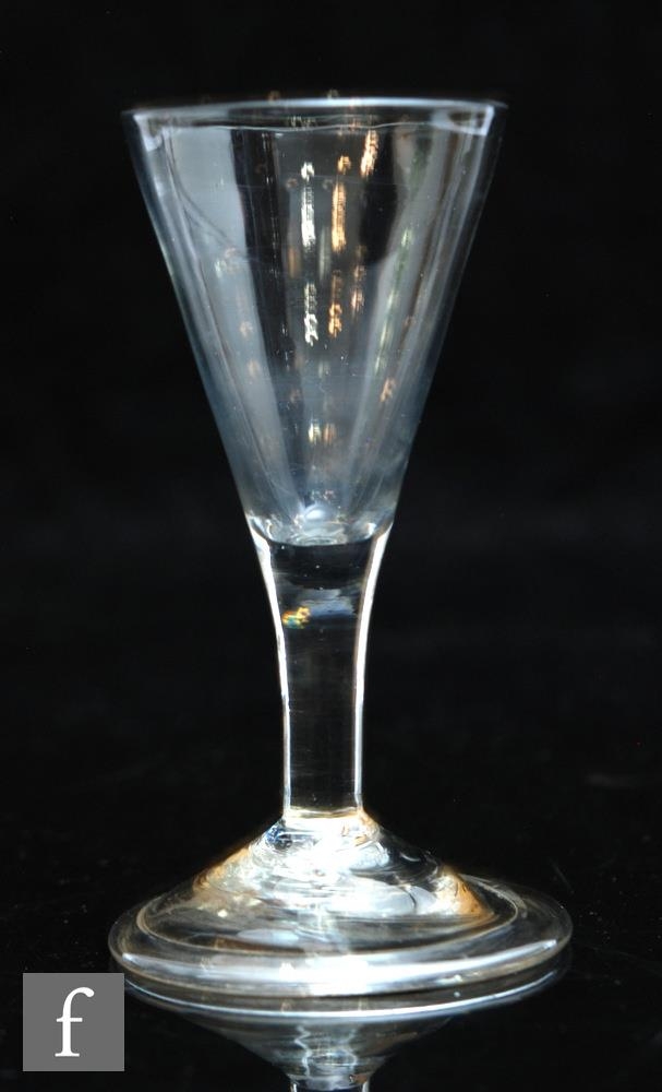 An 18th Century dram glass circa 1750, the conical bowl above a plain stem and raised to a domed and