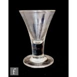 An 18th Century dram glass circa 1750, the drawn trumpet bowl above a plain stem, raised to a