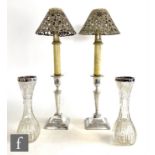 A pair of hallmarked silver candlesticks with square bases below flaring columns and circular scones