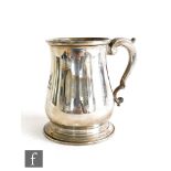 A hallmarked silver pint tankard of plain form with circular stepped base and engraved seated dragon