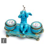 A late 19th to early 20th Century Sevres inkwell modelled as a cherub holding drumsticks, sat beside