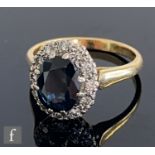 An 18ct sapphire and diamond cluster ring, central oval sapphire within a border of twelve diamonds,