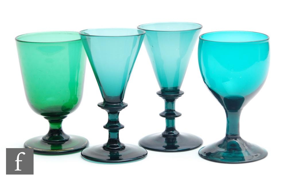 A pair of early 19th Century green wine glasses circa 1815, the drawn funnel bowls on an angular