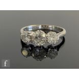 An 18ct white gold diamond three stone ring, brilliant cut claw set stones to knife edged shoulders,